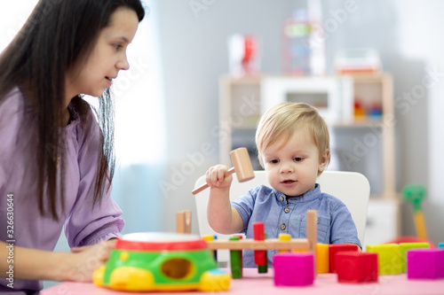 Mother and toddler son play with educational toys together at home