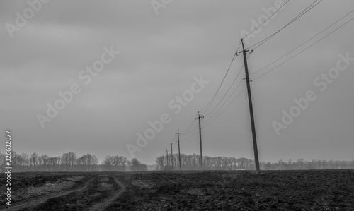road through a field under a cloudy sky