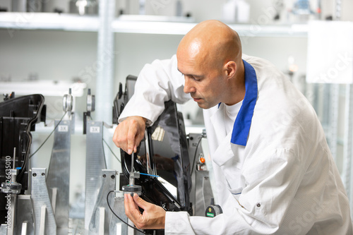 Quality engineer measuring plastic components by digital meter on the fixture, automotive and metrology concept