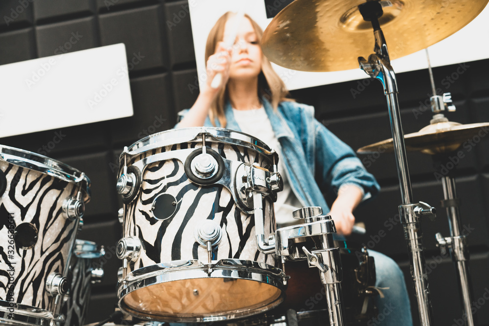 Fototapeta premium Creativity and music. Young beautiful girl plays the drums. Recording Studio. Musical equipment.