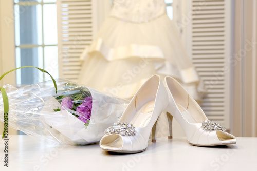 Wedding, white dress and white women's shoes. Bouquet of flowers. Wedding fashion and decor