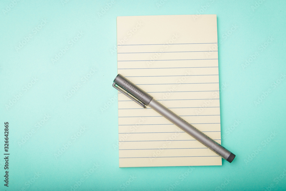 notebook,pen, on turquoise background. top view copy space notebook,pen, on turquoise background. top view copy space