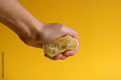 Hand crushes a piece of fresh lemon