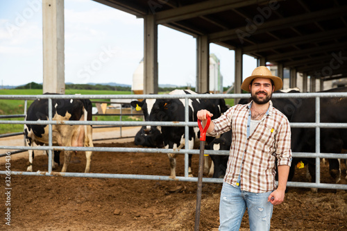 Man farmer standing near cow on background at farm outdoor