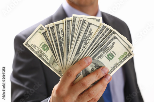 Man in suit and tie hold in arm pack of hundred dollar bills closeup. Stock market, exchange, earn pile, rich present, gift, employer prepayment, service gratitude concept