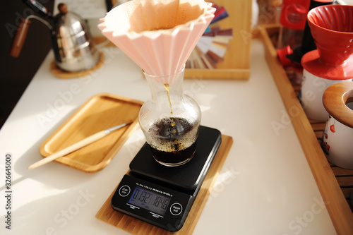 Alternative manual coffee brewing. Pink ceramic origami dripper on electronic scale