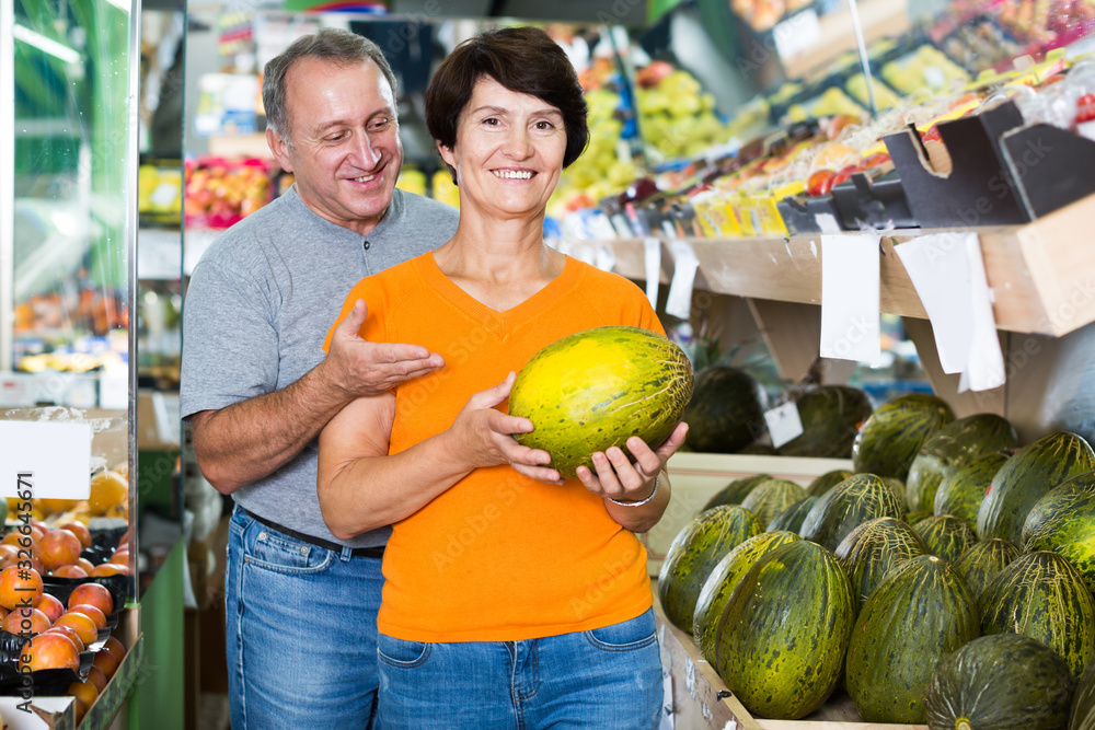Fototapeta premium Man and his wife are choosing ripe melon