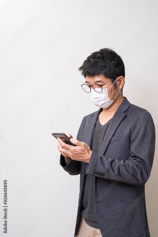 Asian man wearing surgical mask to prevent flu disease Coronavirus and using mobile phone Asian man wearing surgical mask to prevent flu disease Coronavirus and using mobile phone