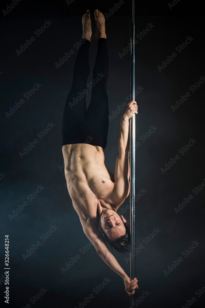Strong young man performing a pole dance Strong young man performing a pole dance