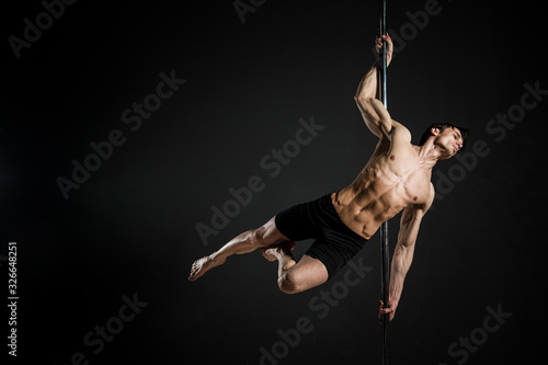 Portrait of male model performing a pole dance