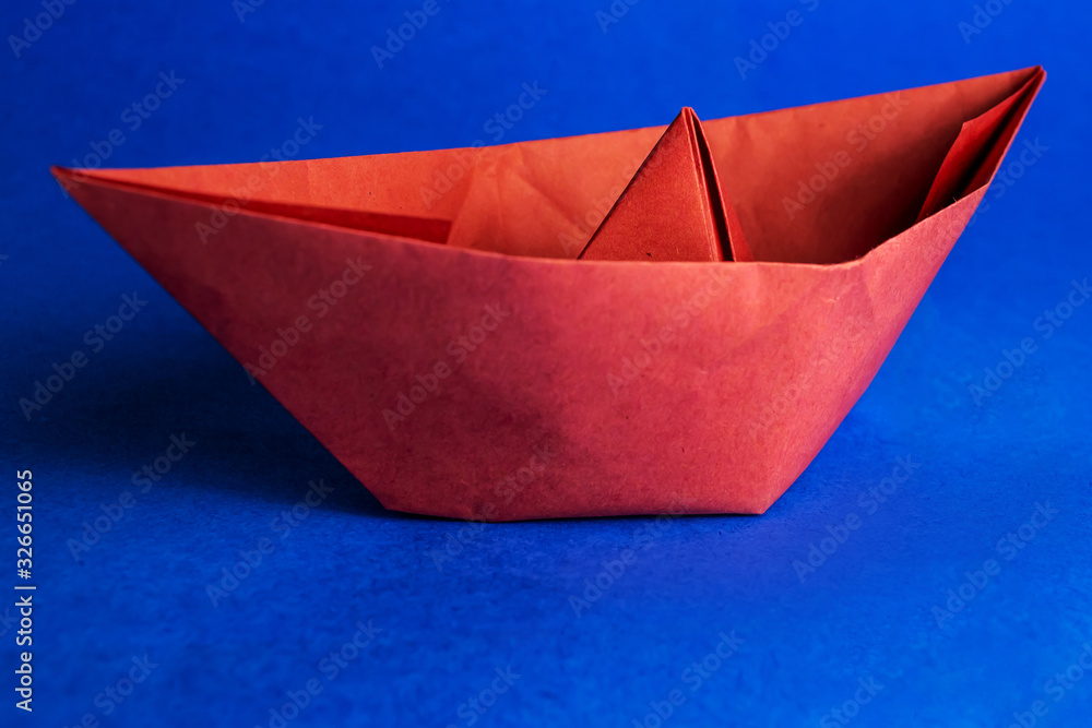 Red paper boat on a blue background