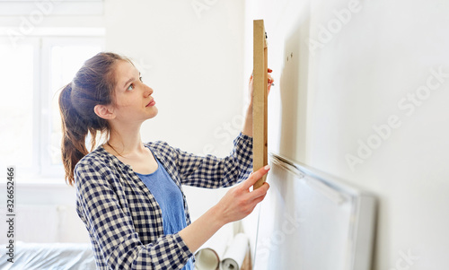 Junge Frau als Heimwerker beim Bild aufhängen