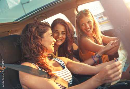 Three female friends enjoying road trip traveling at vacation in the car. © Zoran Zeremski