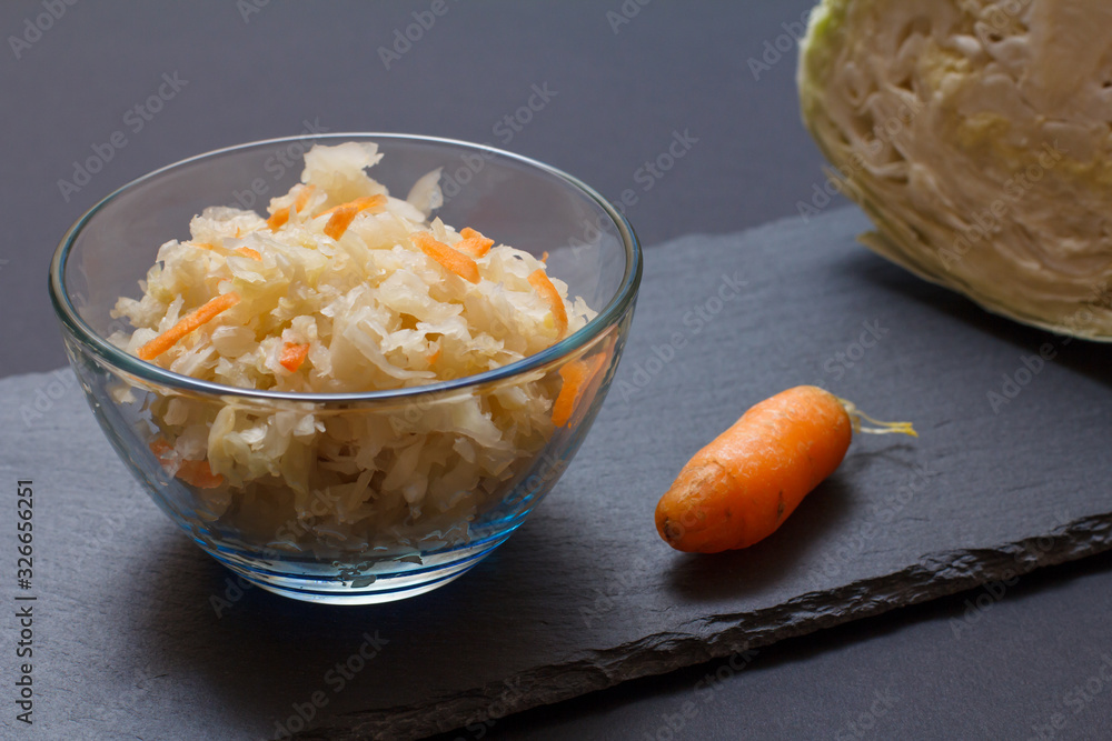 Fermented cabbage with herbs and spices in glass bowl on the black background Fermented cabbage with herbs and spices in glass bowl on the black background