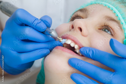 A woman dentist doctor brushes the teeth of a teenage child with a special medical brush. Inspection of the oral cavity of the girl. Modern technologies in dentistry. photo