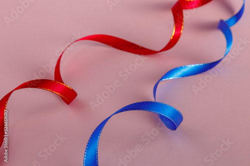 Red and blue ribbons on a pink background. Selective focus