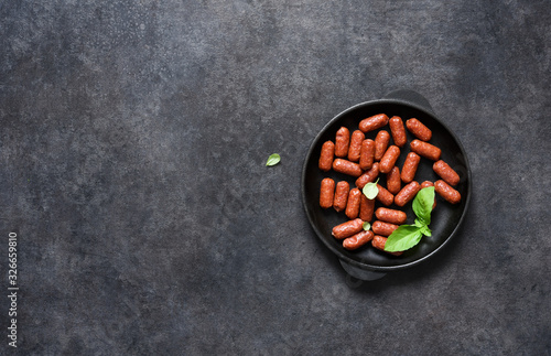 Spicy chorizo sausages in a cast-iron pan on a black background with place for text.