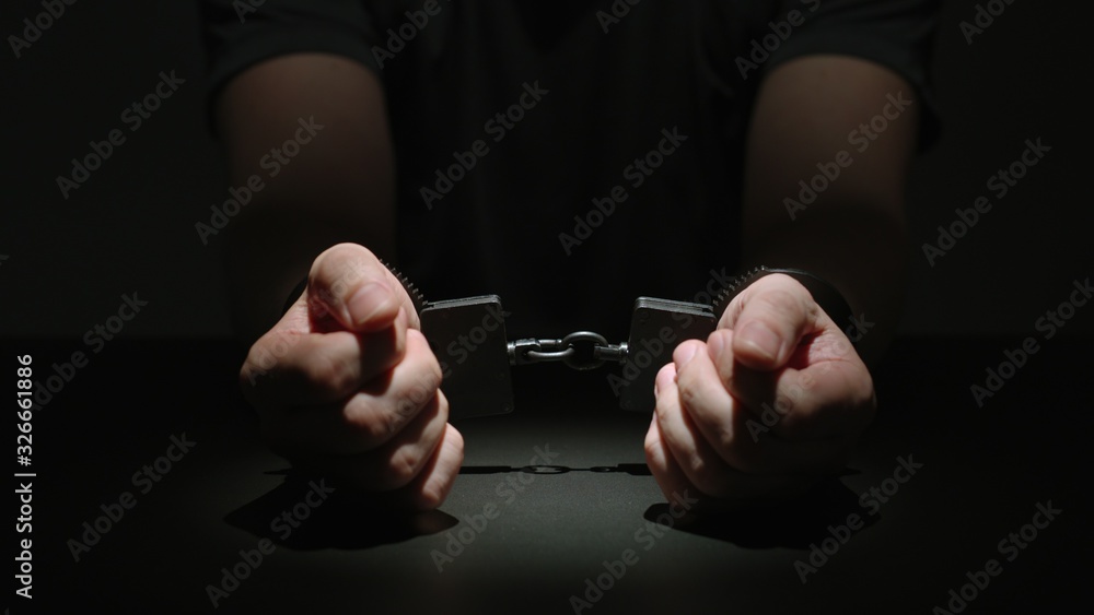 Man Putting His Handcuffed Hands On A Black Table Man Putting His Handcuffed Hands On A Black Table