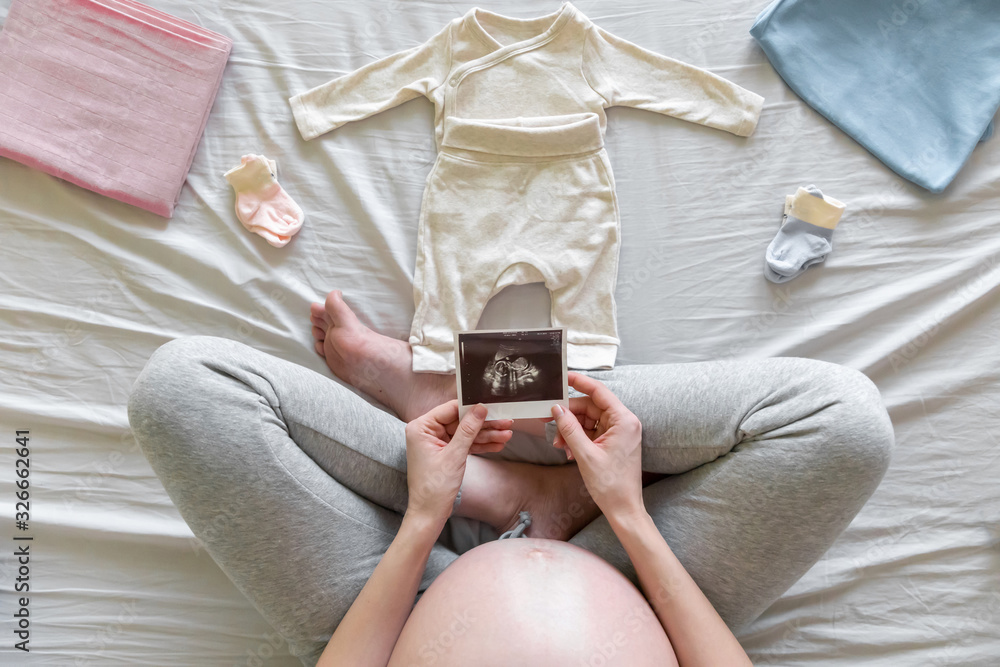 Φωτογραφία Top view of expecting pregnant woman in bed looking at ultrasound scans, boy or