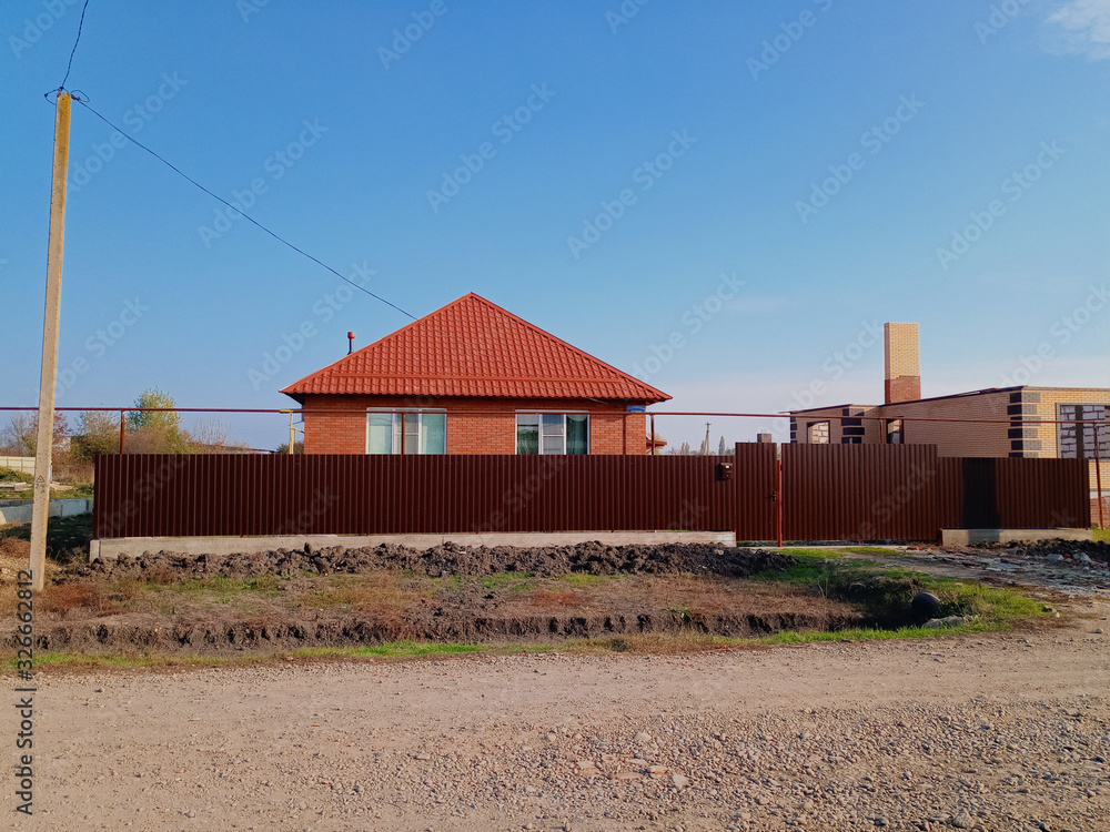 new house with an orange roof and a brown fence.