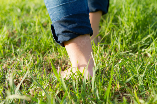 woman barefoot walking on green and long grass