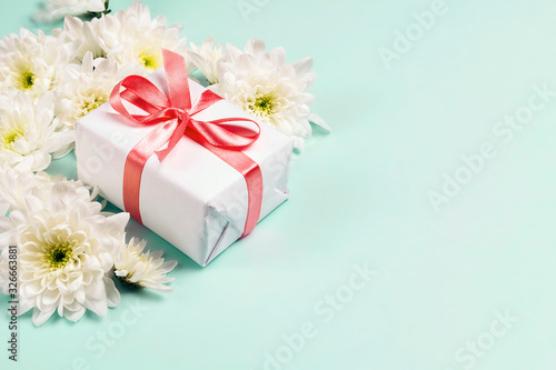 Gift box with chrysanthemum flowers on a blue background. Copy space, top view. © WindyNight