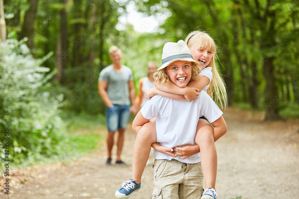 Fototapeta premium Junge trägt lachende Schwester huckepack