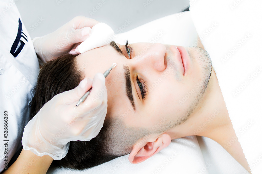 Naklejka premium Manual face cleansing at the beautician. A man on the procedure for treating facial skin from acne.