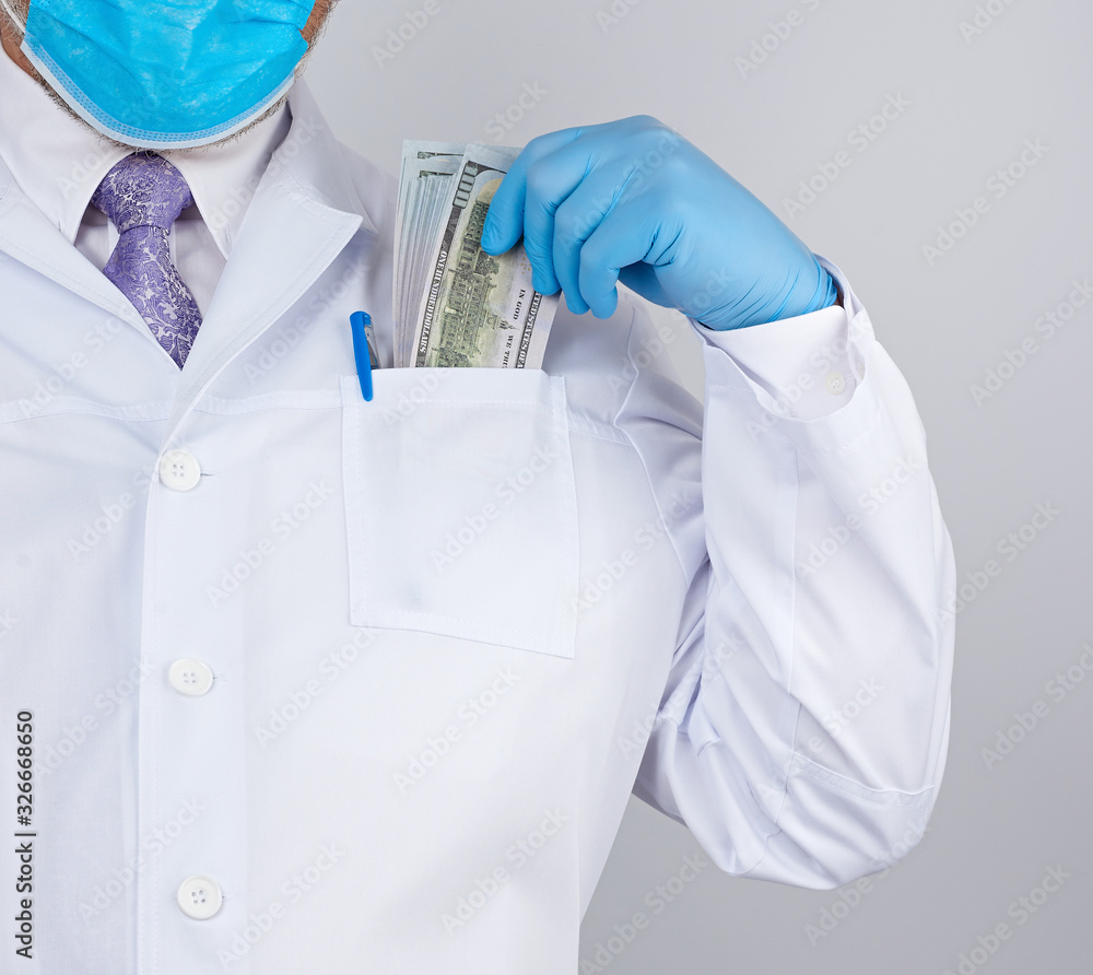 physician in a white coat, wearing blue sterile gloves, doctor holds a pack of paper money physician in a white coat, wearing blue sterile gloves, doctor holds a pack of paper money