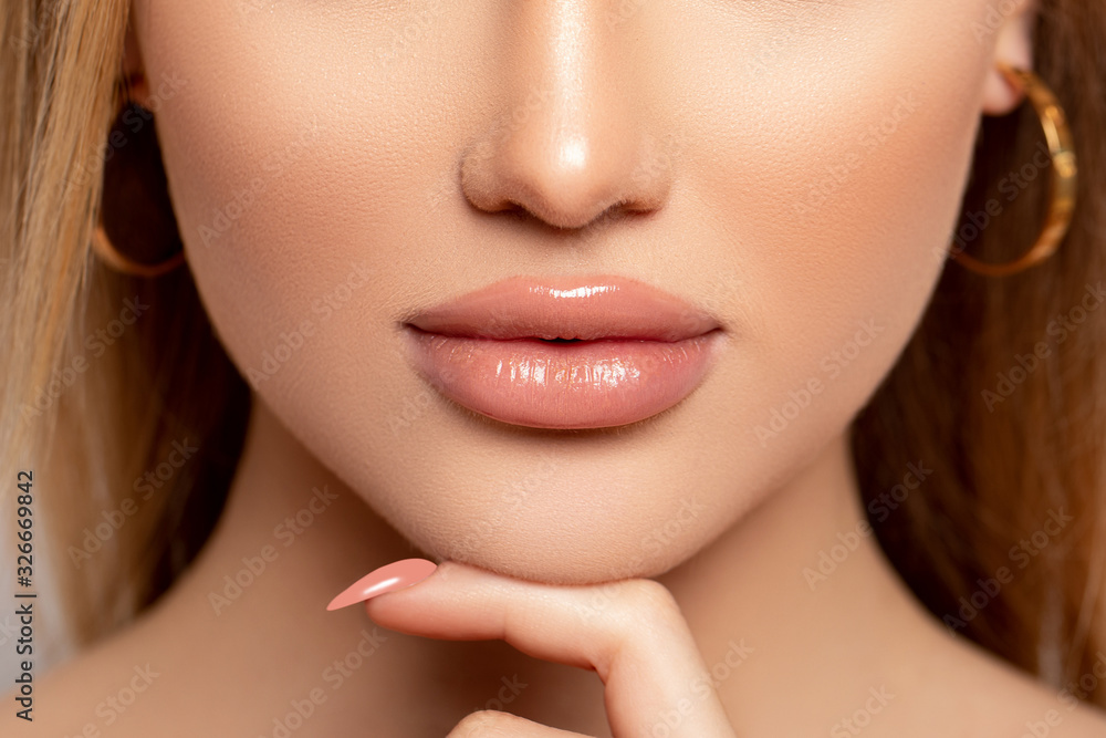 Fototapeta premium Sexy Lips. Make up. Close up Beautiful photo Lips. Manicure. Beauty Fashion Woman Lips with natural Makeup. shine Lipstick. Isolated. Macro Mouth Caramel Colors lacquered model touches her lips 
