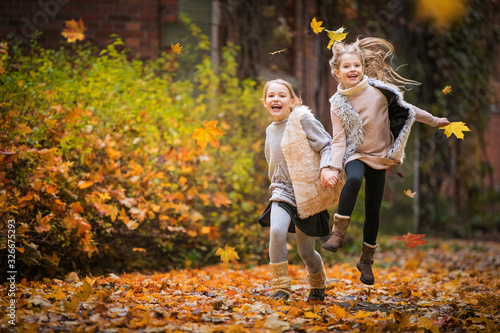 Two girls have fun running in the autumn park