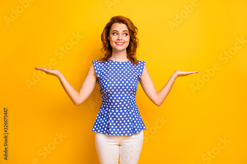 Portrait of her she nice attractive lovely cute smart glad cheerful cheery wavy-haired girl holding on palms invisible pros cons scales isolated on bright vivid shine vibrant yellow color background