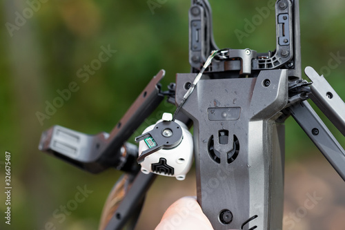 Pilot holding in hand broken black quadcopter drone uav after crash accident outdoors . Remote control failure due to strong wind interference. Cracked camera gimball plastic legs