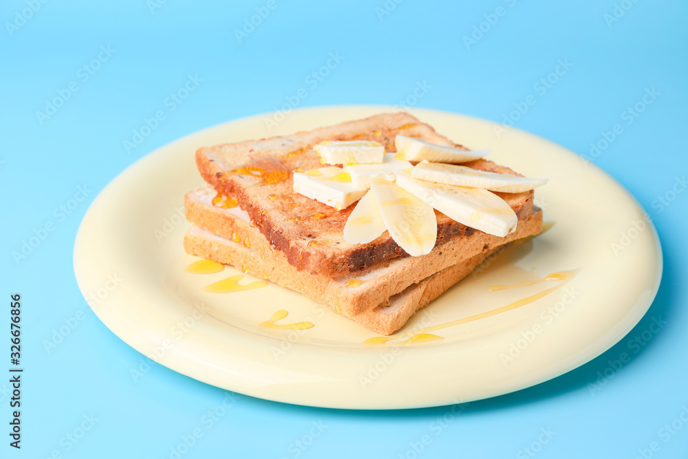 Tasty toasted bread with honey, butter and banana on color background Tasty toasted bread with honey, butter and banana on color background