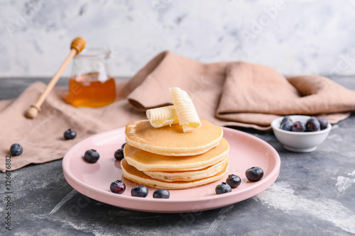 Tasty pancakes with butter and berries on table