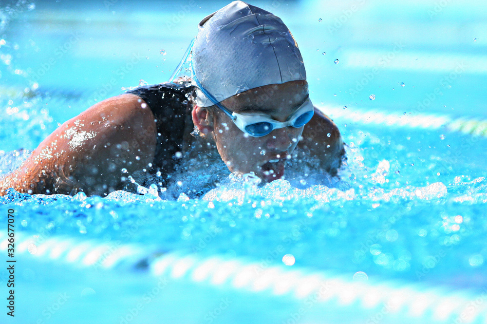 nadadora competindo de touca e óculos na piscina