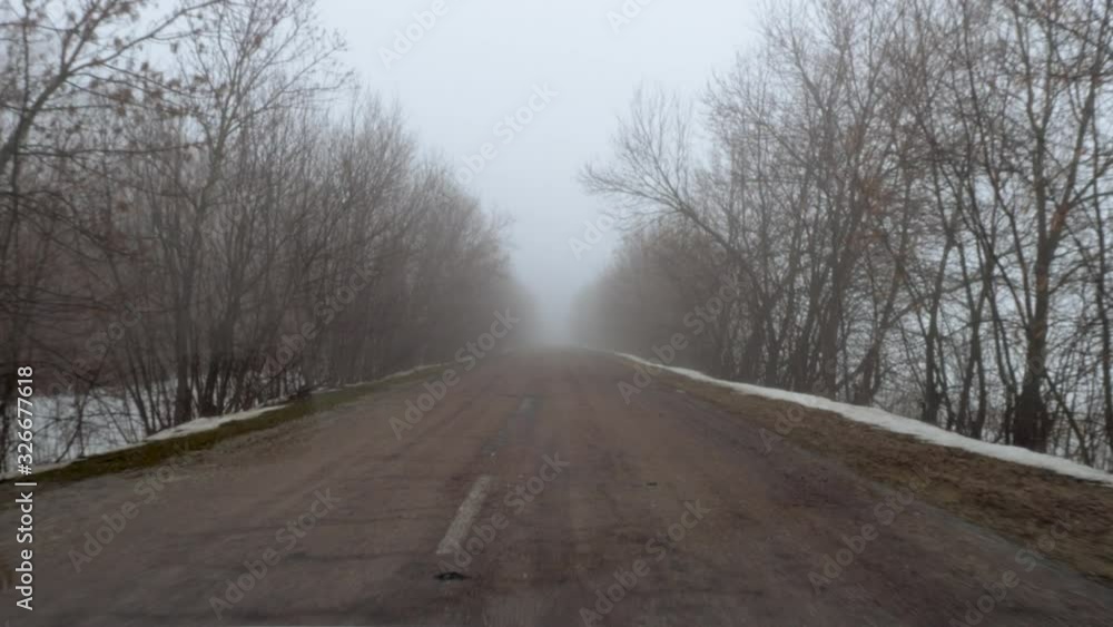 Winter landscape. View through windscreen of a car driving on country road surrounded fields and trees covered by thick fog. 4K Winter landscape. View through windscreen of a car driving on country road surrounded fields and trees covered by thick fog. 4K