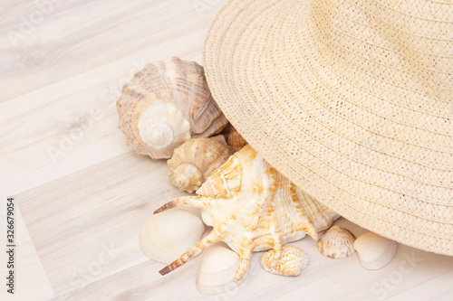 Seashells and straw hat on a wooden light background. Travel and vacation concept.