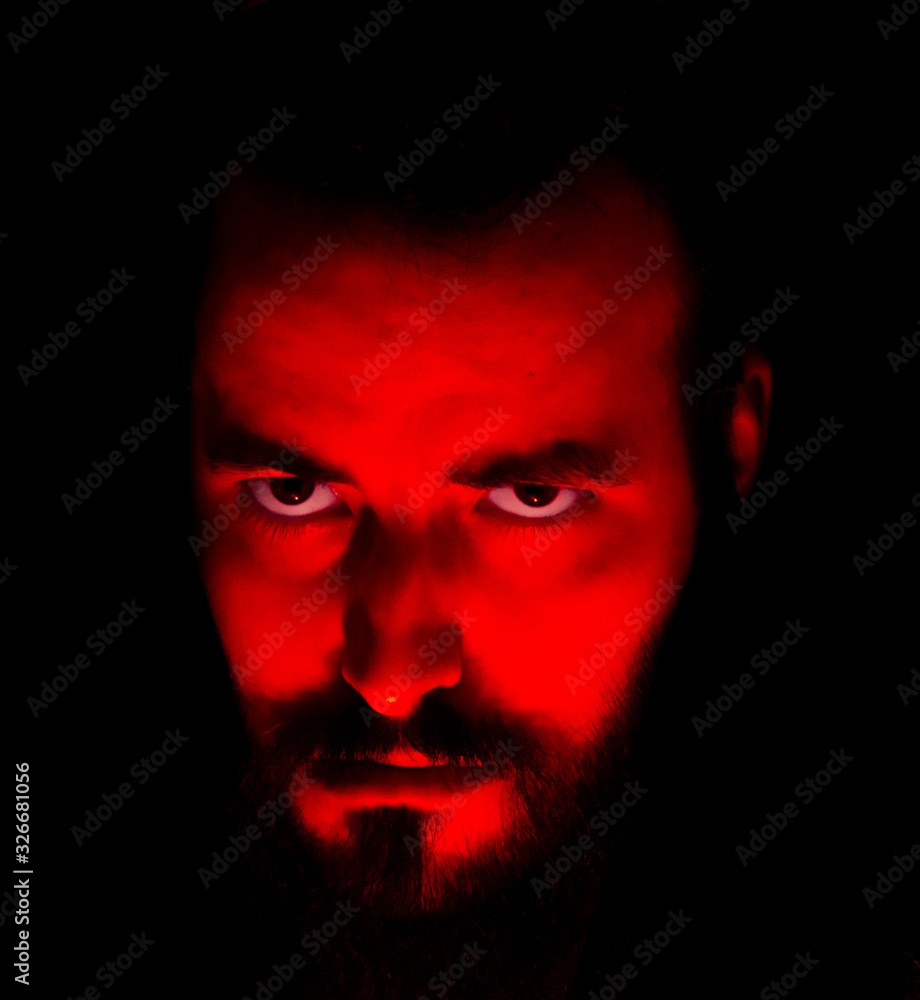 bearded boy with red light on his face worrying fear and tyrant look. bearded boy with red light on his face worrying fear and tyrant look.