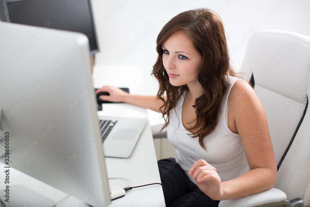Young woman working on a computer in a home office Young woman working on a computer in a home office