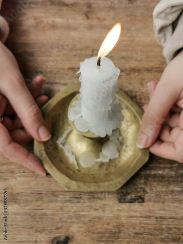 Young Female Hands Holding a candle on a holder | candlestick over a Wooden Table | Top view | high angle above shot