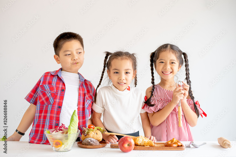 Group of little Asian girls and boy express happy and fun emotion with various food on table with white background.