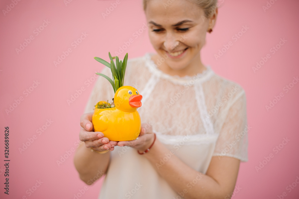 Girl holding a flower pot in the shape of duck with the yellow narcissus with green leaves Girl holding a flower pot in the shape of duck with the yellow narcissus with green leaves