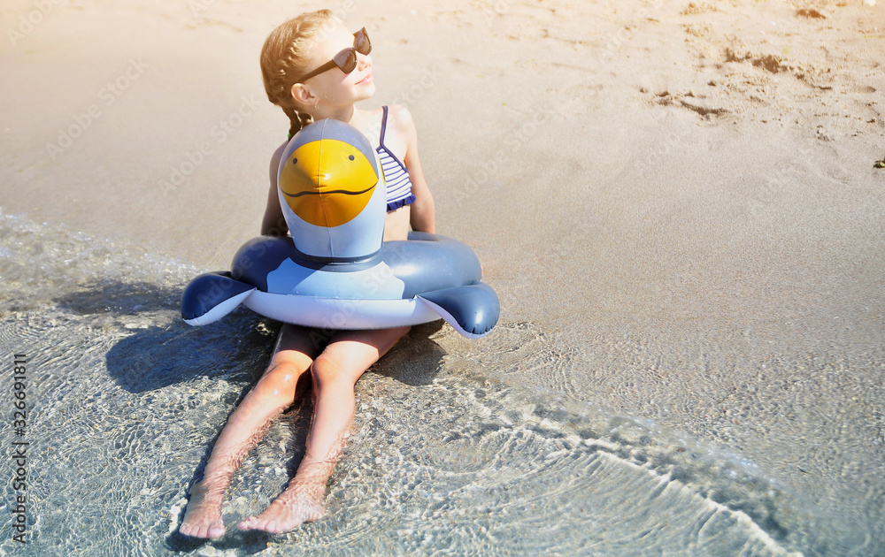 Obraz premium Summer time. Little girl with rubber ring has fun on the beach.