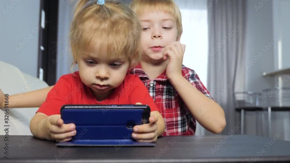 children watch online video on a smartphone. little boy and girl brother sister watch online streaming broadcasting cartoons on the phone lifestyle children watch online video on a smartphone. little boy and girl brother sister watch online streaming broadcasting cartoons on the phone lifestyle