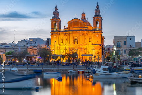 Valletta harbour with yachts and fishing boats, Msida Parish Church of Saint Joseph at sunset, Malta photo