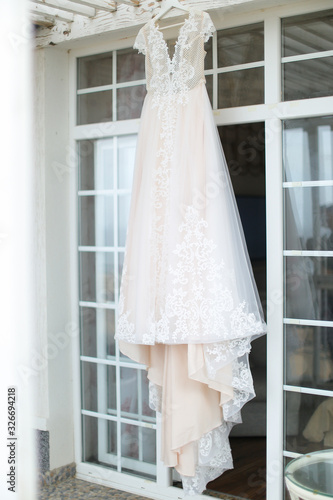 White bridal amazing dress hanging on hanger outdoors. photo