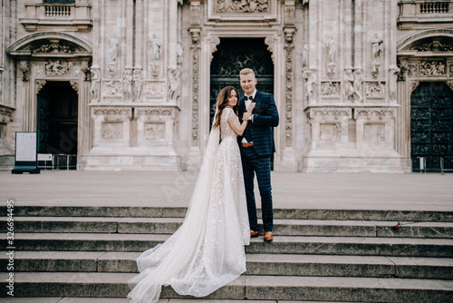 groom and bride posing in front of the church