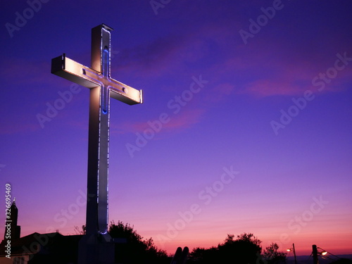 Cross on purple sunset background. Copie space