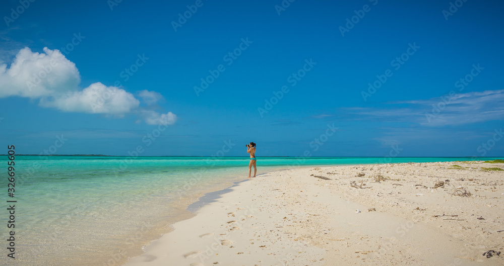 Young woman taking picture at the beach. Noronqui Cay Los Roques National Park, Venezuela